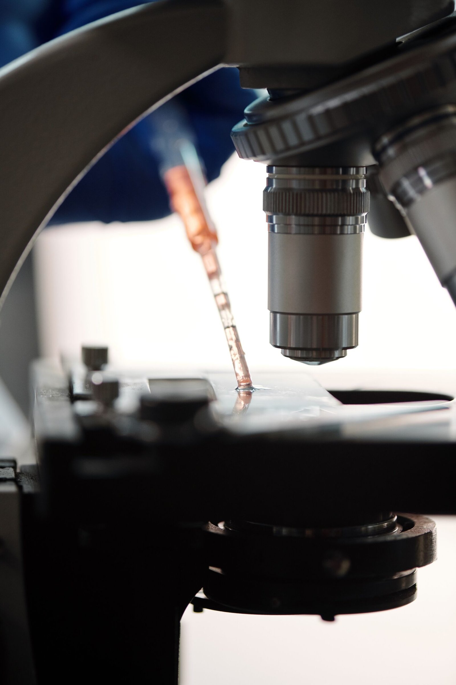 Detailed view of a microscope and pipette in a laboratory setting, highlighting scientific research.