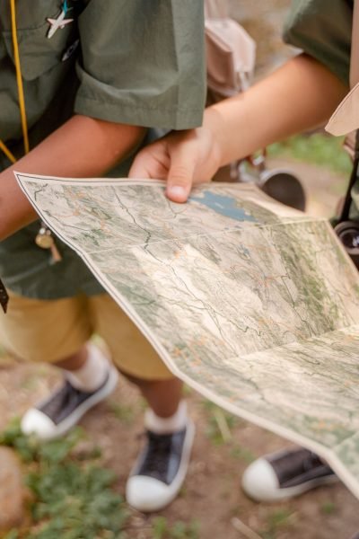 Two scouts examining a map with compass in hand, capturing the essence of navigation outdoors.